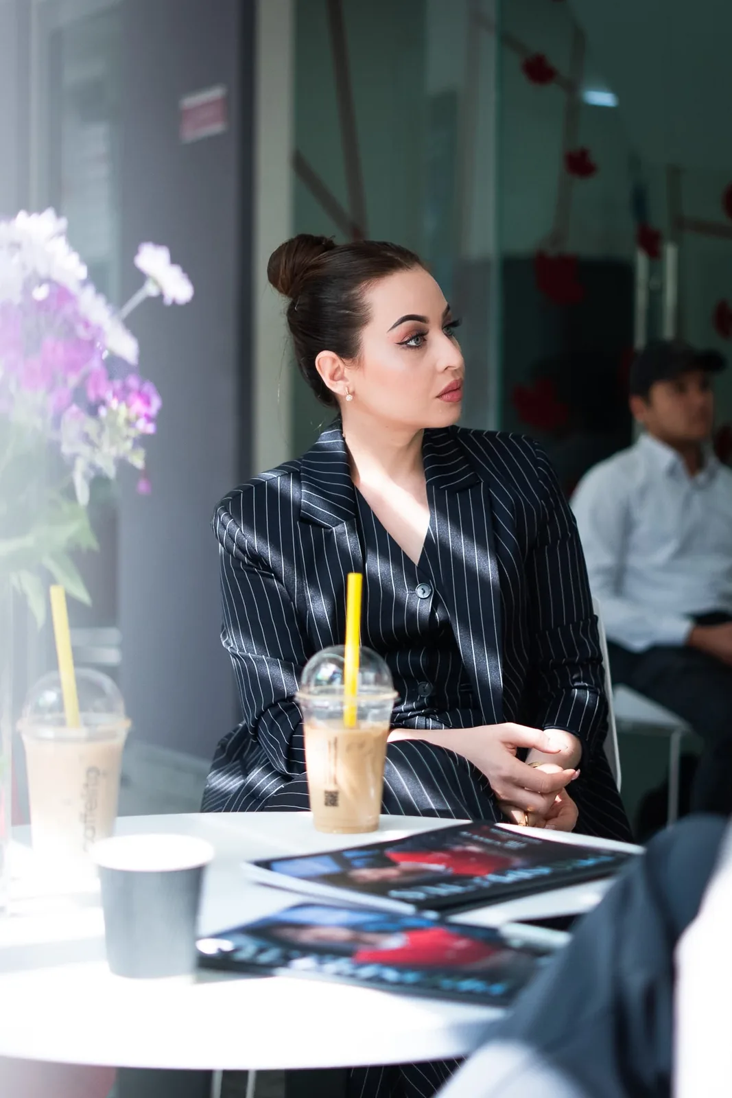 A guest seated at a caf&eacute; table with the CST magazine and iced coffee