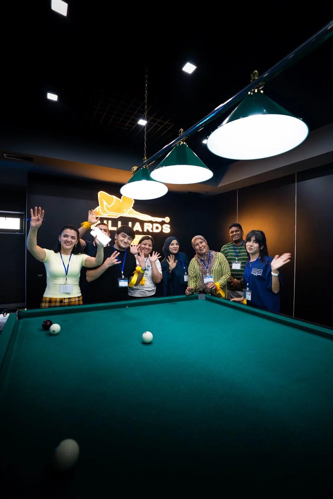 Colleagues waving from around a billiards table