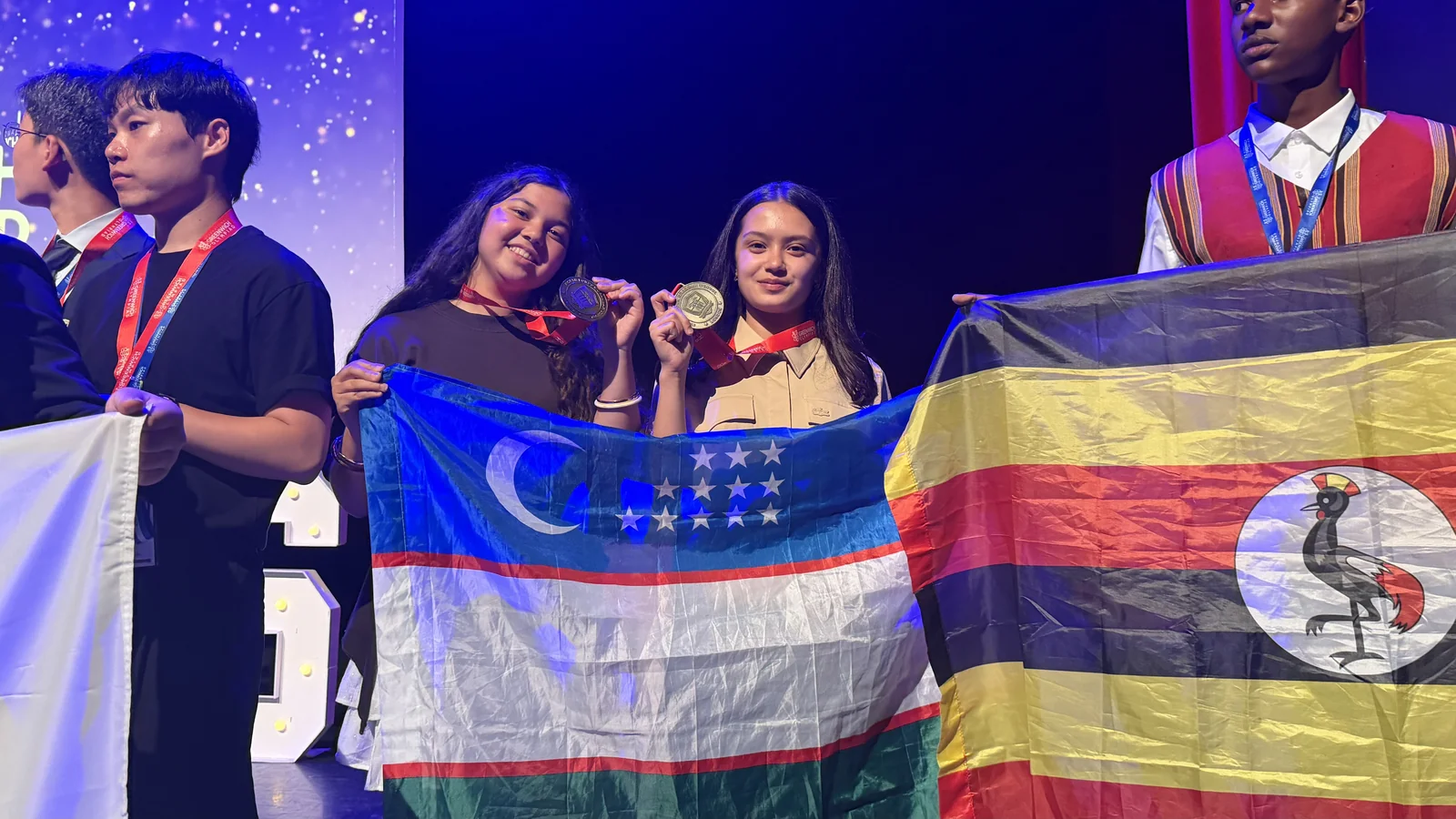 CST&rsquo;s gold medallists on stage at the IGO 2026 finals, holding the flag of Uzbekistan