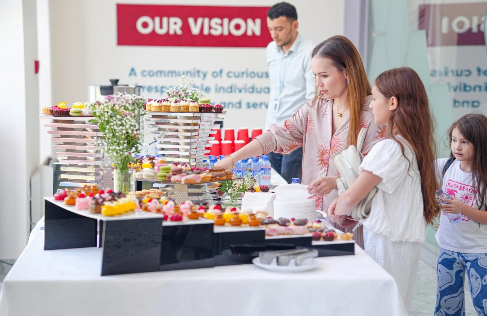 Families at a welcome reception on the CST campus, beneath the school&rsquo;s Our Vision wall